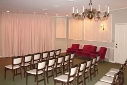 A room with rows of chairs and a chandelier.