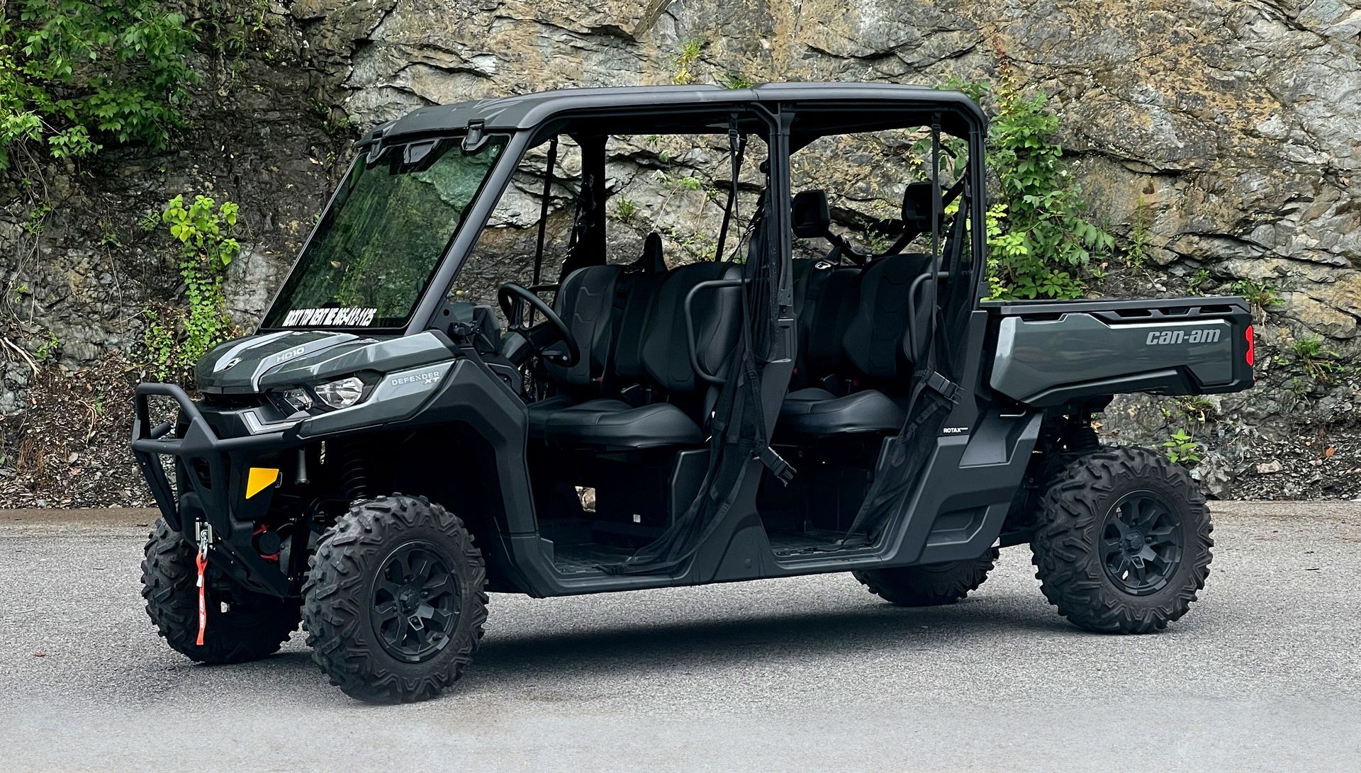 A black atv is parked on the side of the road next to a rock wall.