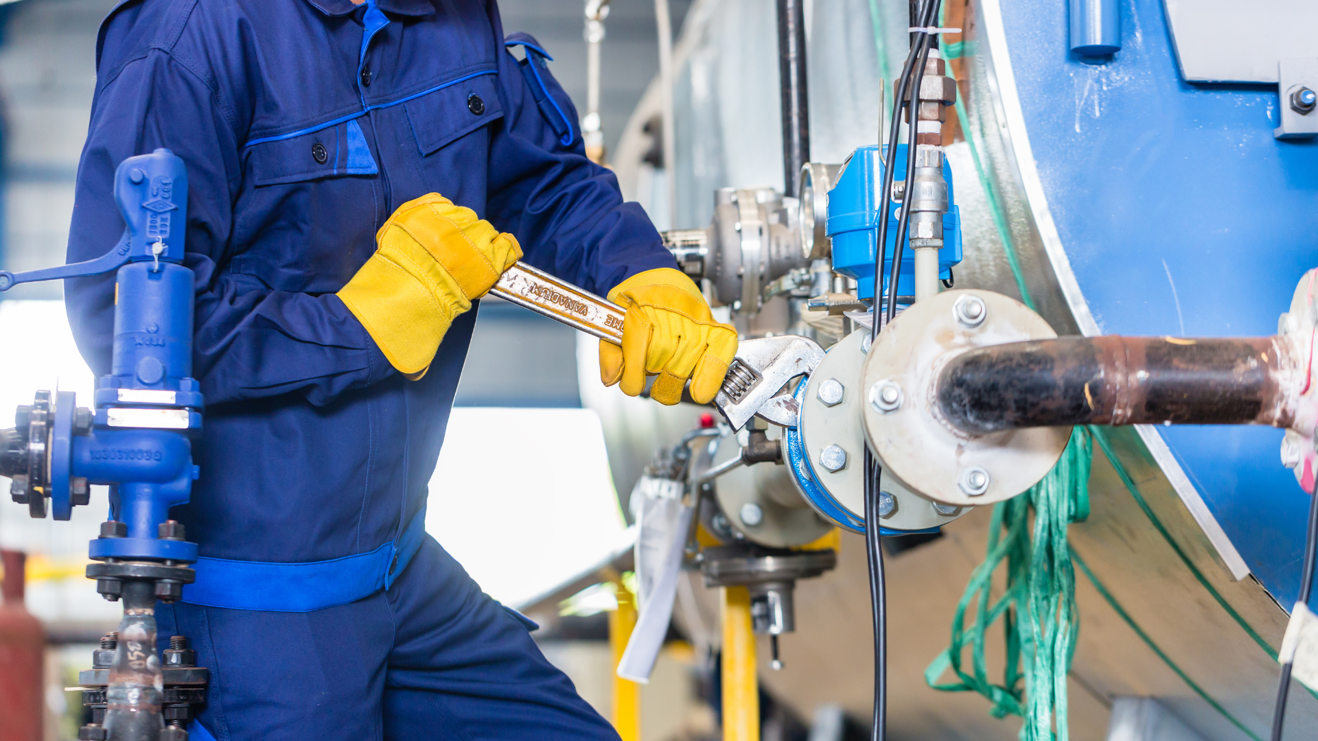A man is working on a pipe in a factory.