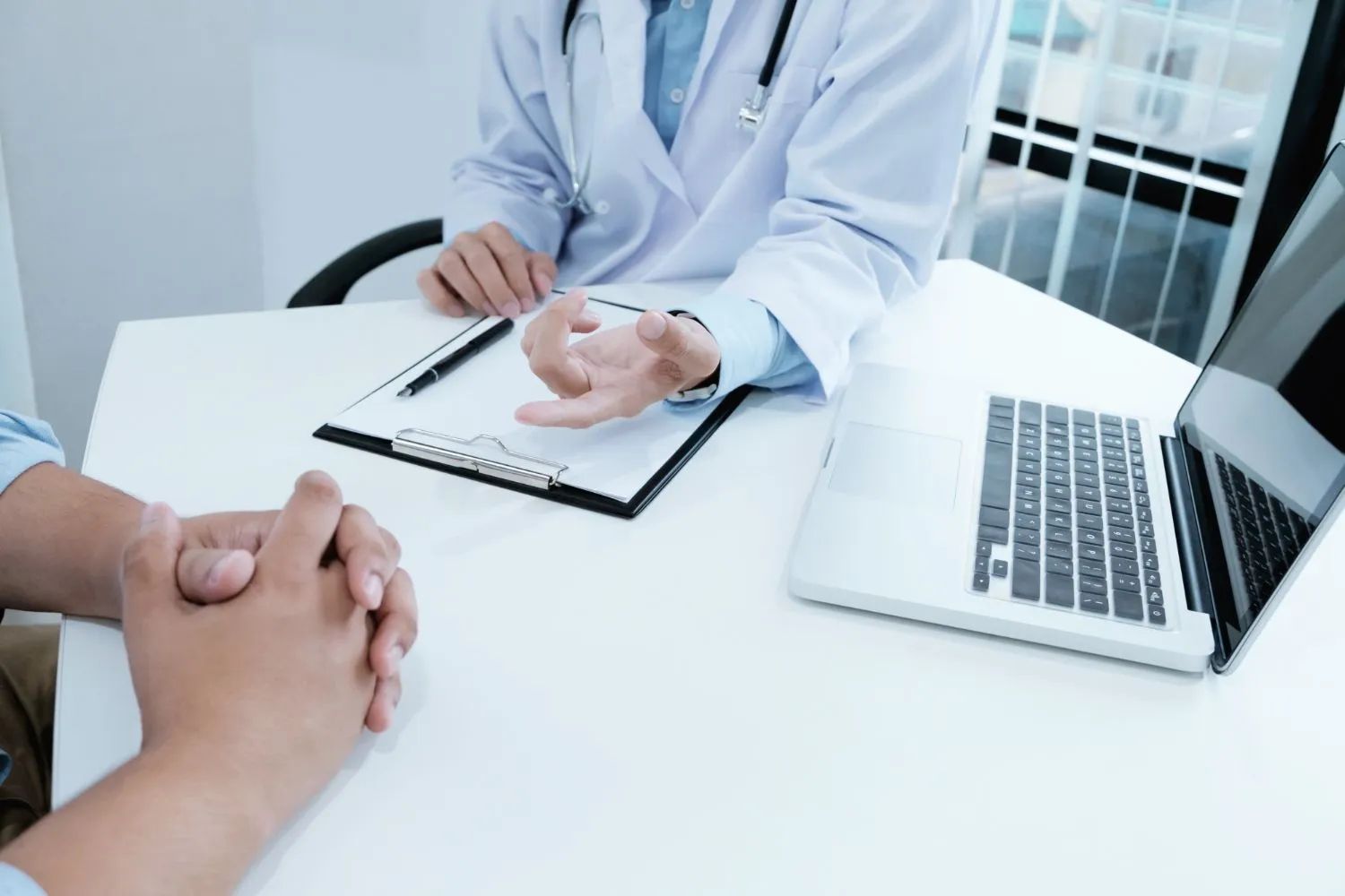 a doctor is talking to a patient at a desk with a laptop