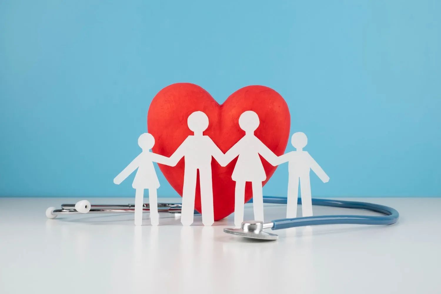 a paper family holding hands in front of a red heart and a stethoscope