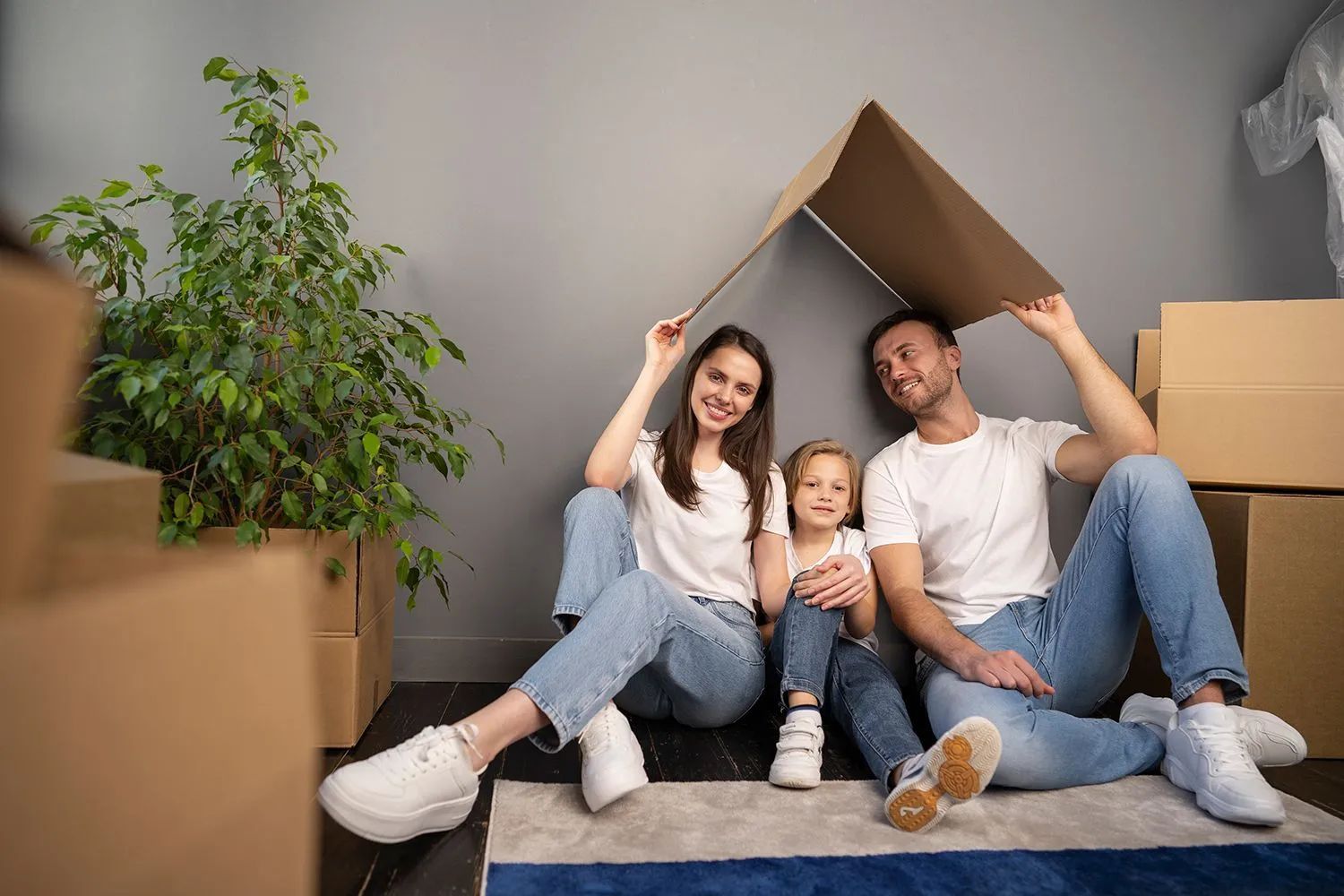 a family is sitting on the floor under a cardboard house