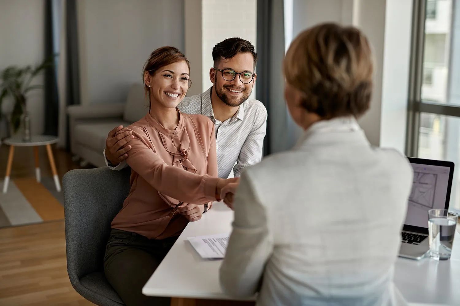 a man and a woman are sitting at a table shaking hands with a woman