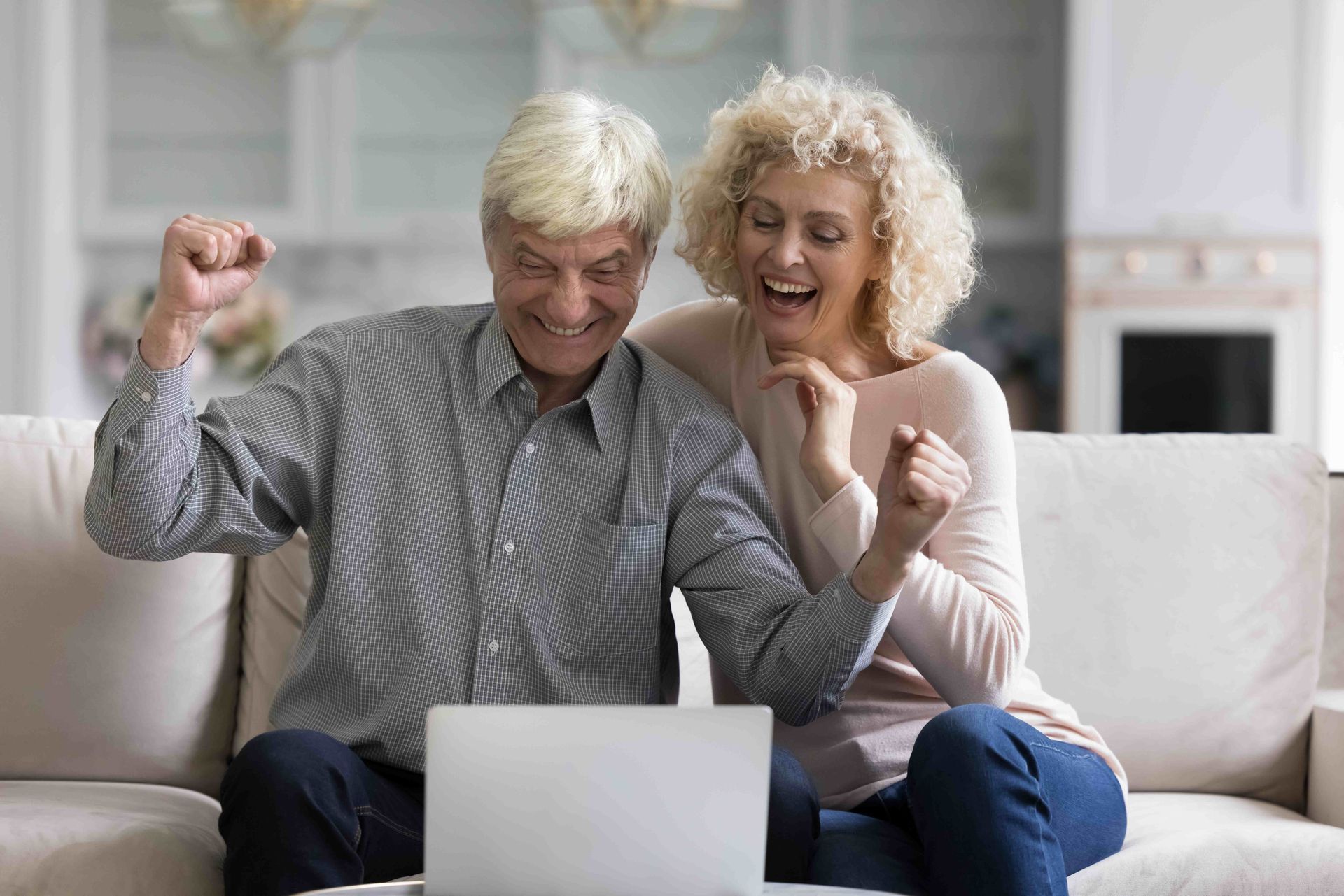 an elderly couple is sitting on a couch looking at a laptop computer