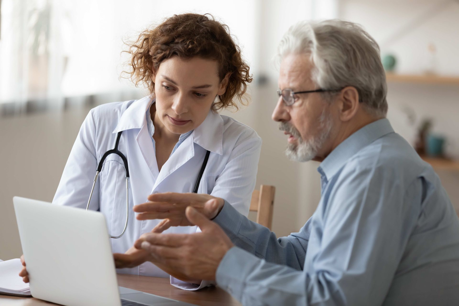 a doctor and a patient are looking at a laptop computer