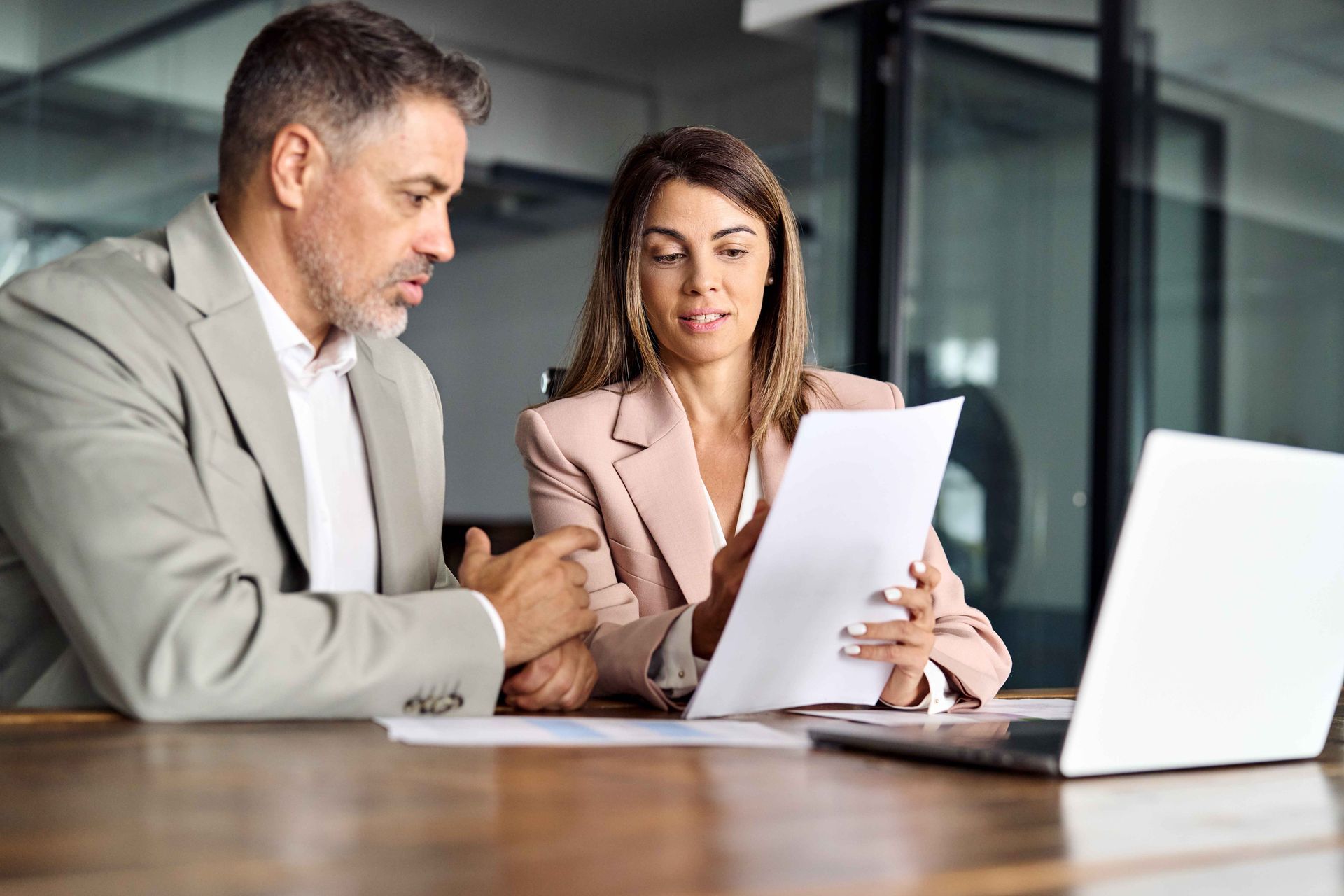 a man and a woman are sitting at a table looking at a piece of paper