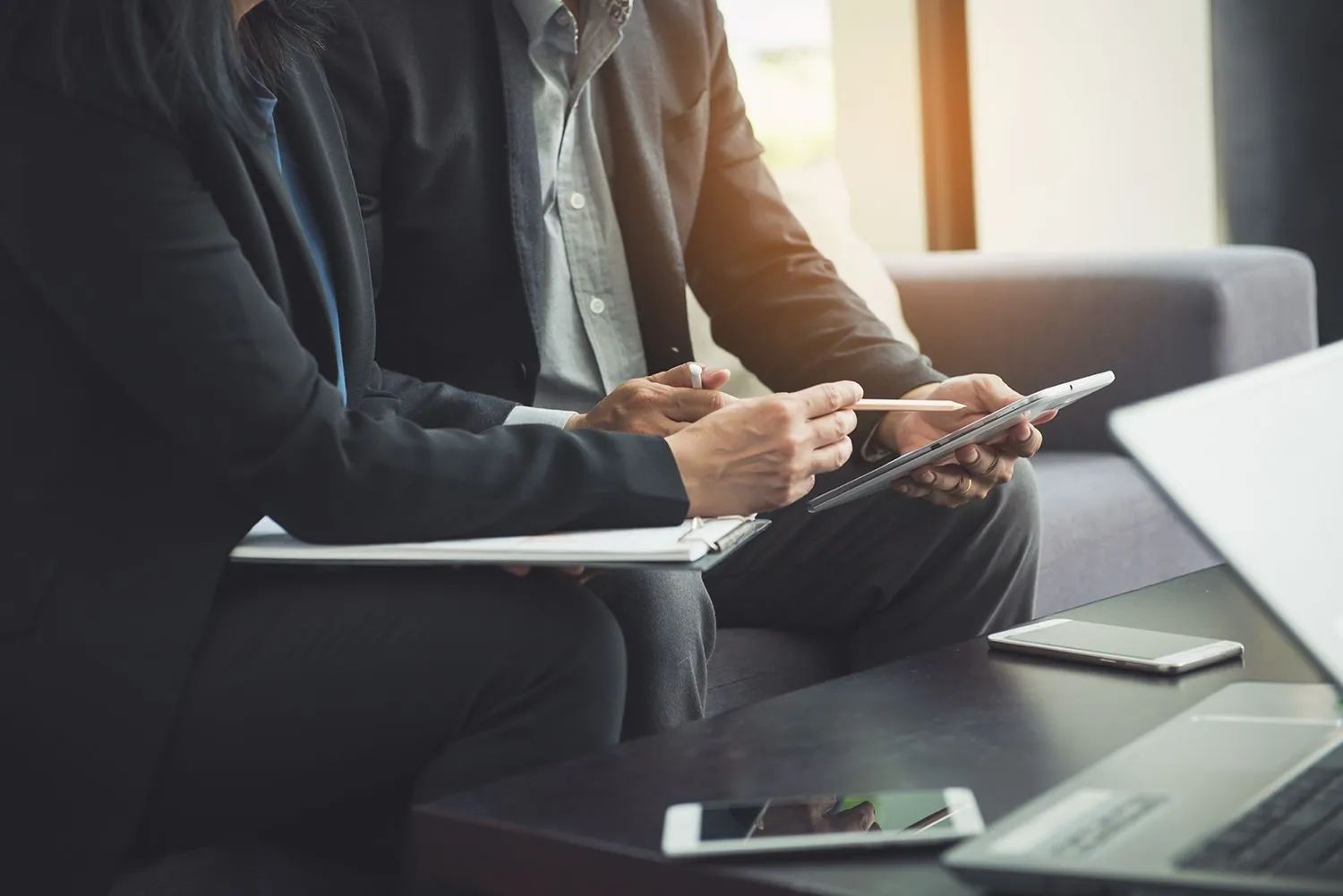 a man and a woman are sitting at a table looking at a tablet