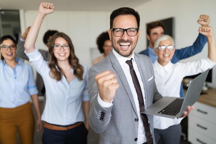 a man is holding a laptop in front of a group of people