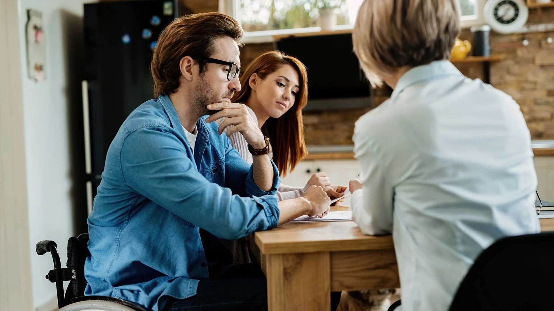 a man in a wheelchair is sitting at a table talking to a woman