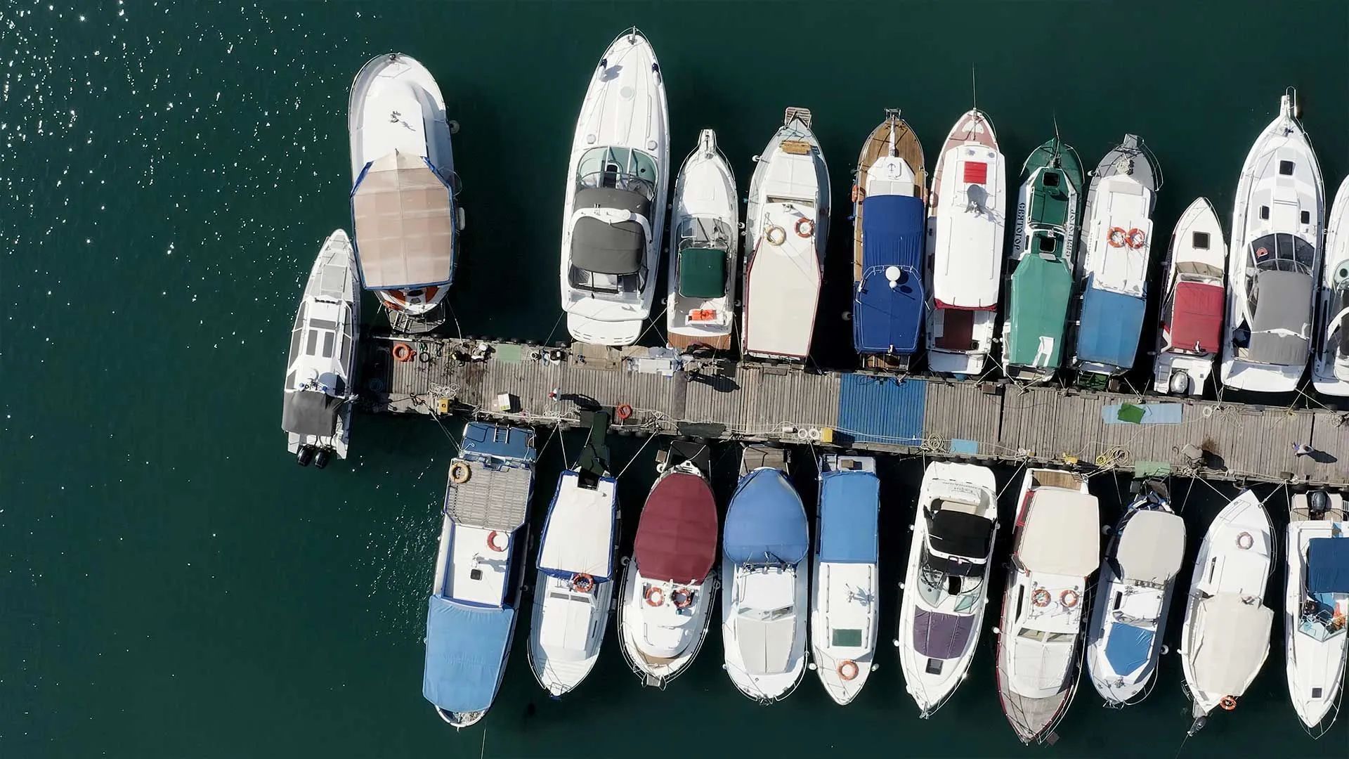 a row of boats are docked at a dock in the water