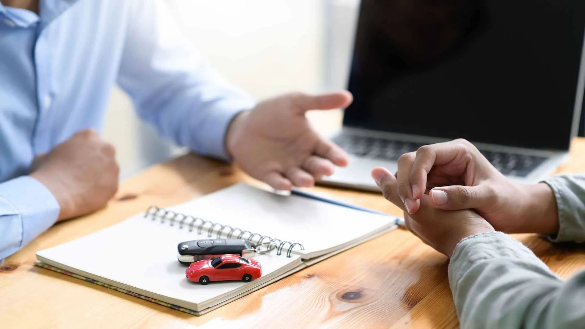 a man and a woman are sitting at a table talking about a car