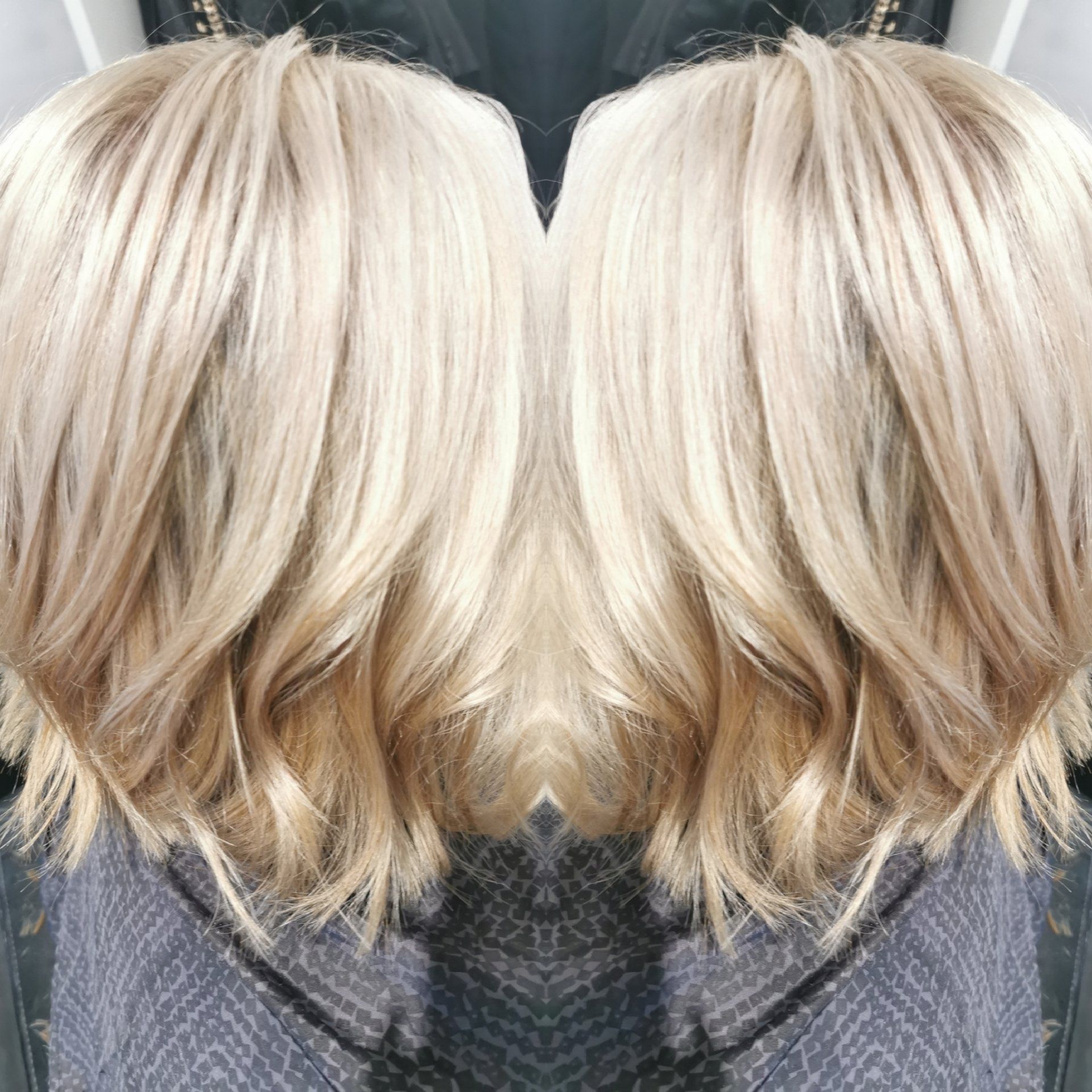 A woman 's blonde hair is reflected in a mirror