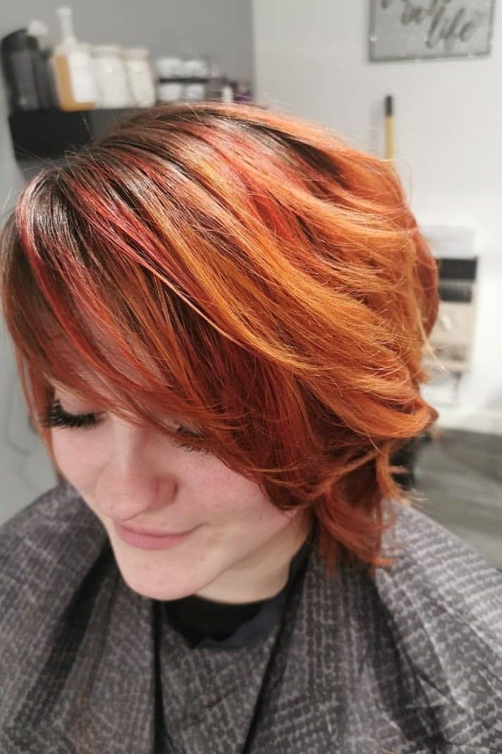 A woman with red hair is sitting in a chair in a salon.