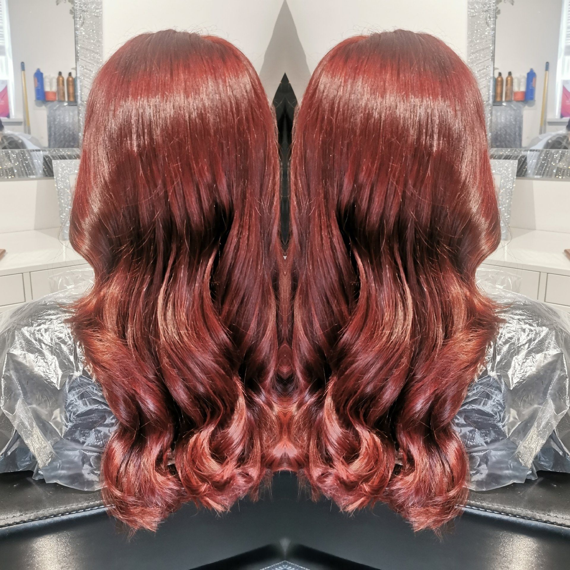 A woman 's hair is reflected in a mirror in a salon.