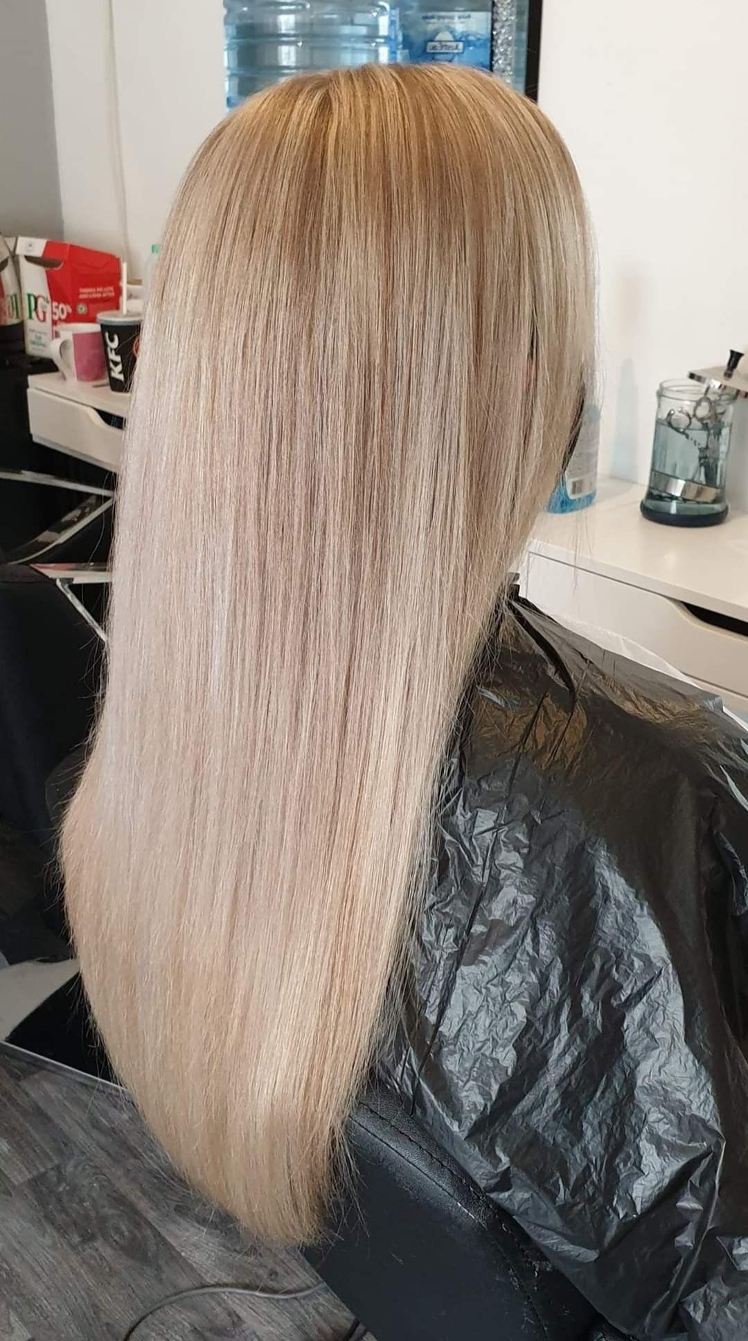 A woman with long blonde hair is sitting in a chair in a salon.