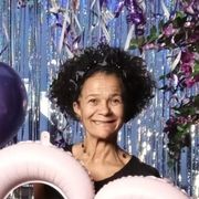 Sari Kangas is holding a balloon and a sign in front of balloons.