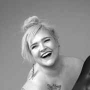 Pipsa with a tattoo on her chest is laughing in a black and white photo.