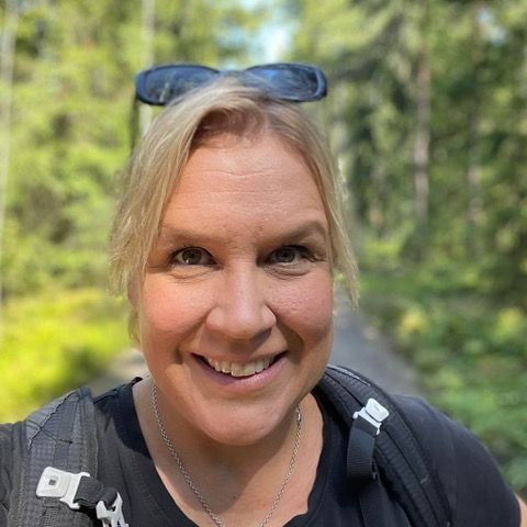 Päivi Illi wearing glasses is smiling for the camera