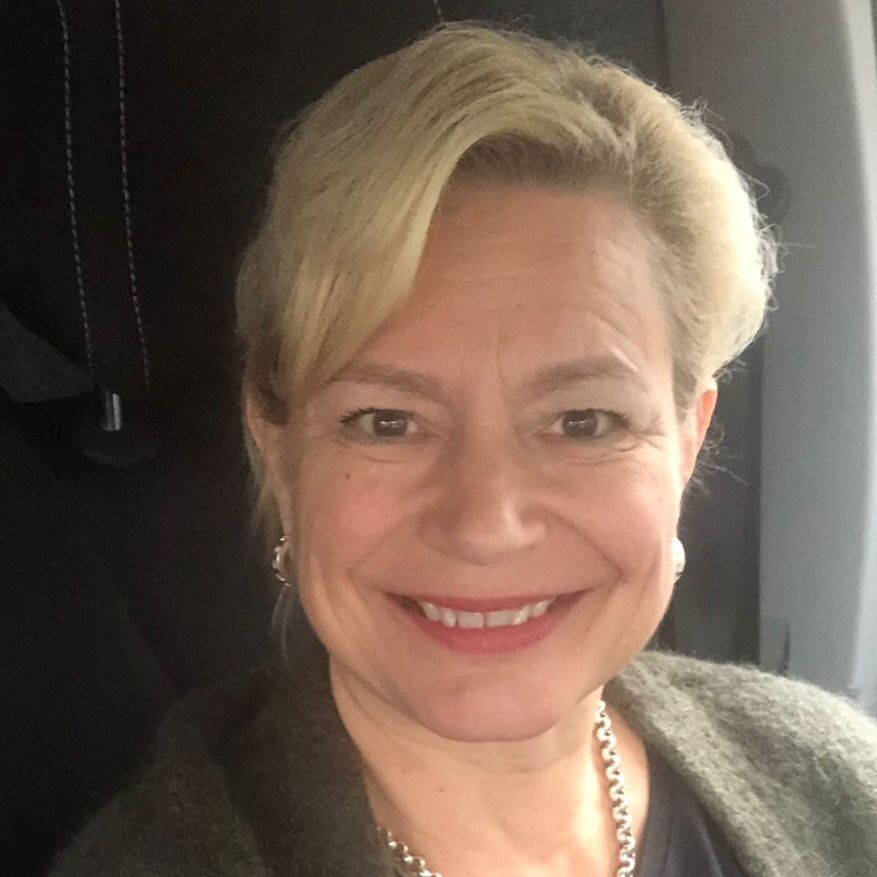 Satu Kanervo wearing sunglasses and a backpack is smiling for the camera.