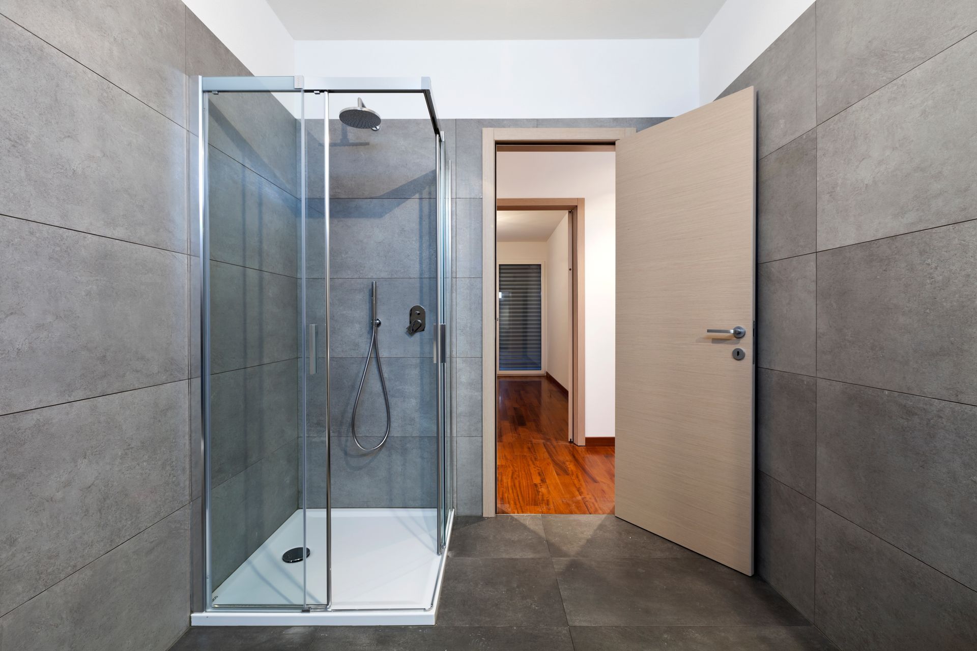 A bathroom with a walk in shower and an open door.
