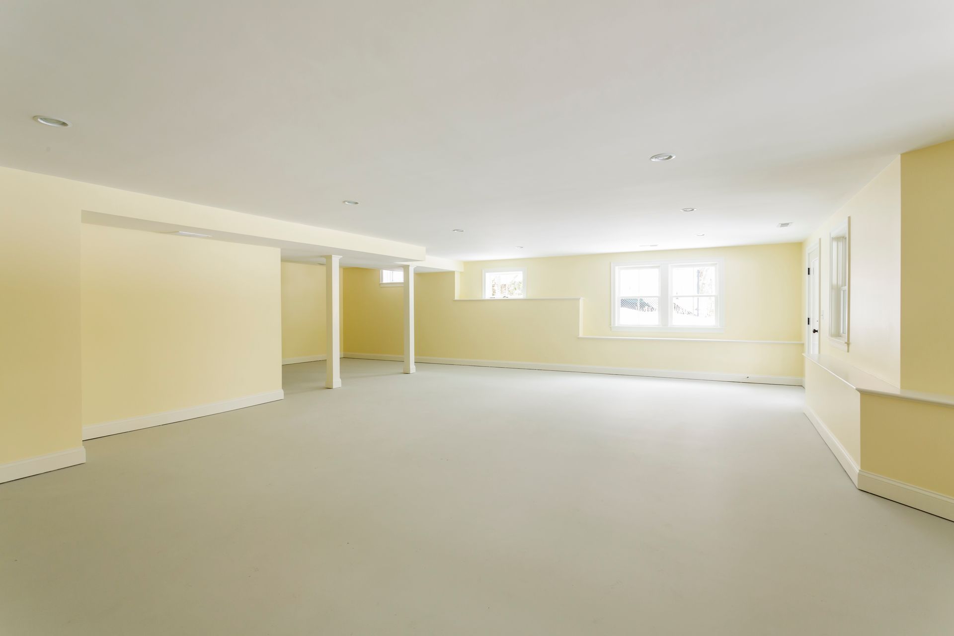 An empty basement with yellow walls and white carpet.