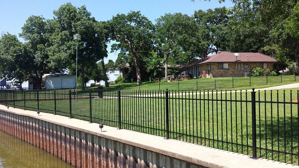 A house is behind a fence next to a body of water.