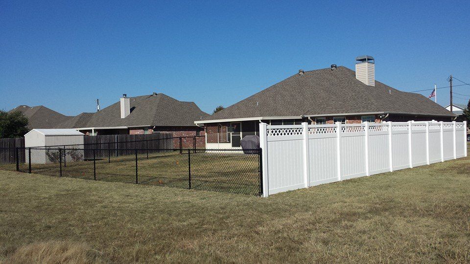 A white fence surrounds a backyard of a house.