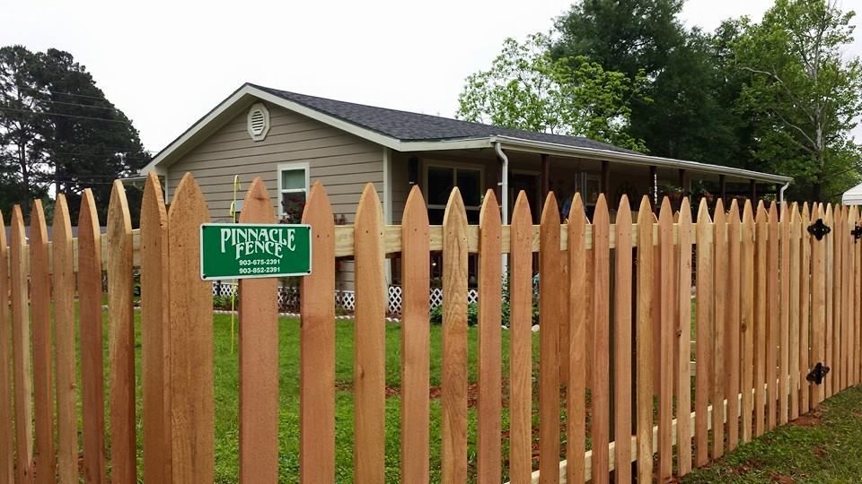 A wooden picket fence with a house in the background