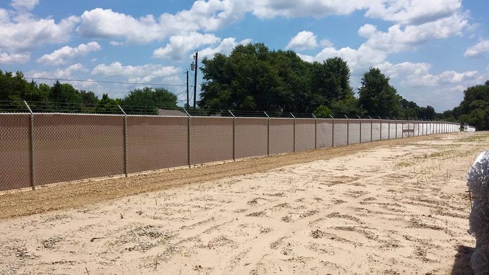 A chain link fence is surrounding a dirt field.