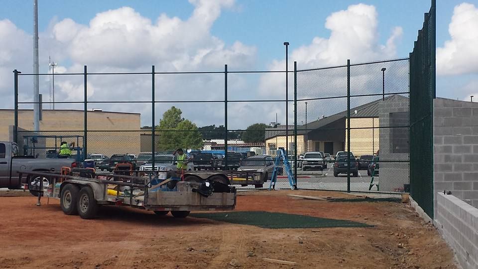 A truck with a trailer attached to it is parked in front of a fence