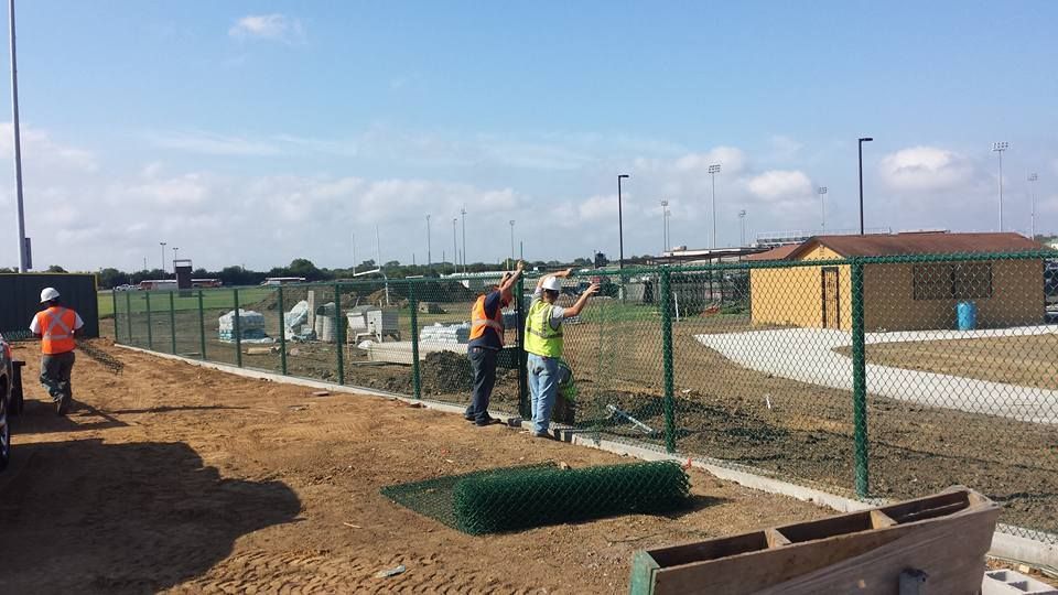 A group of construction workers are working on a chain link fence.