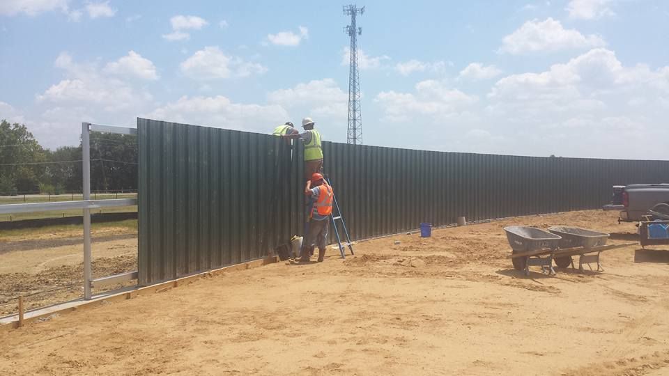 A group of construction workers are working on a fence.