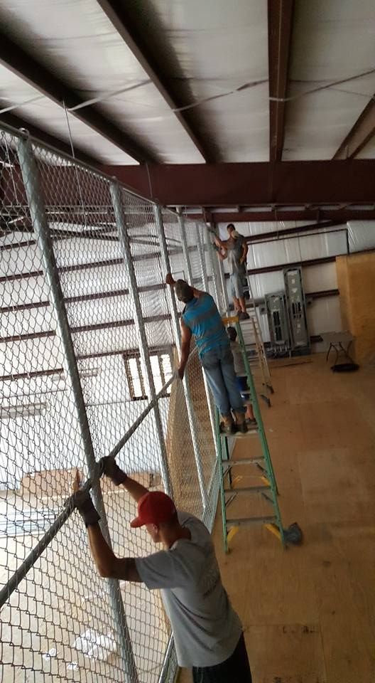 A group of people are working on a chain link fence in a building.