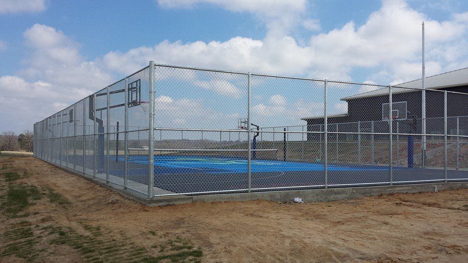 There is a basketball court behind a chain link fence.