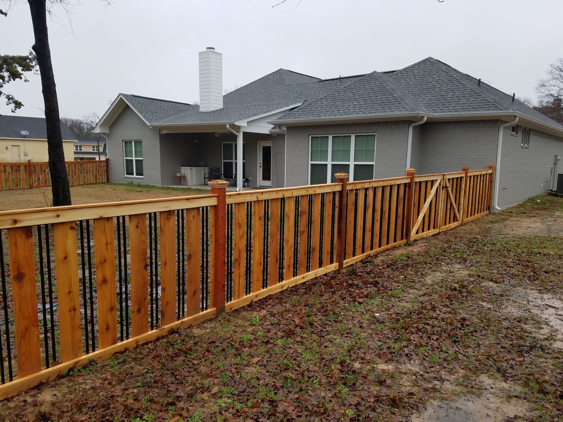 The back of a house with a wooden fence in front of it.