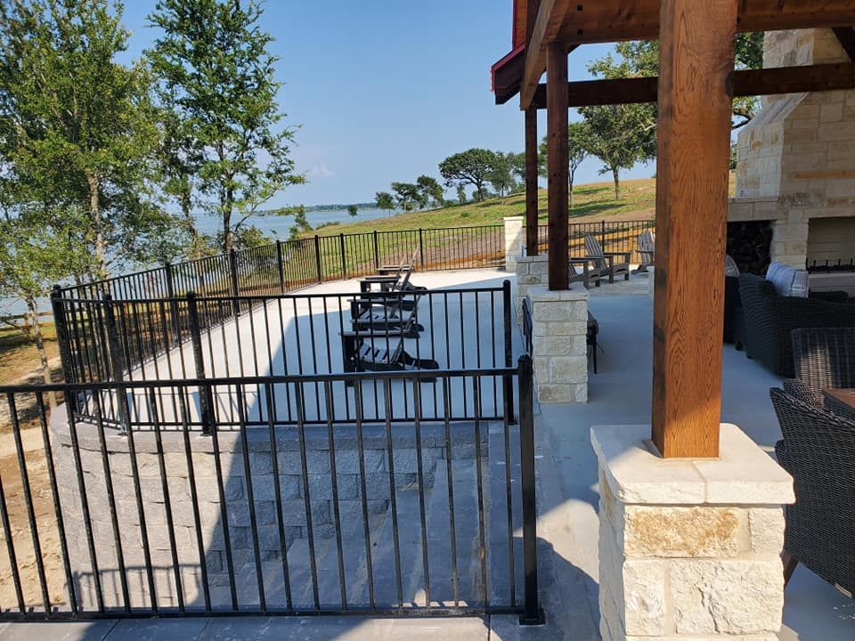 A fence surrounds a patio with a view of a lake.