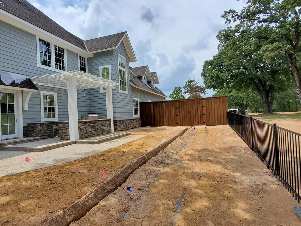 A large house with a fence and a lot of dirt in front of it.