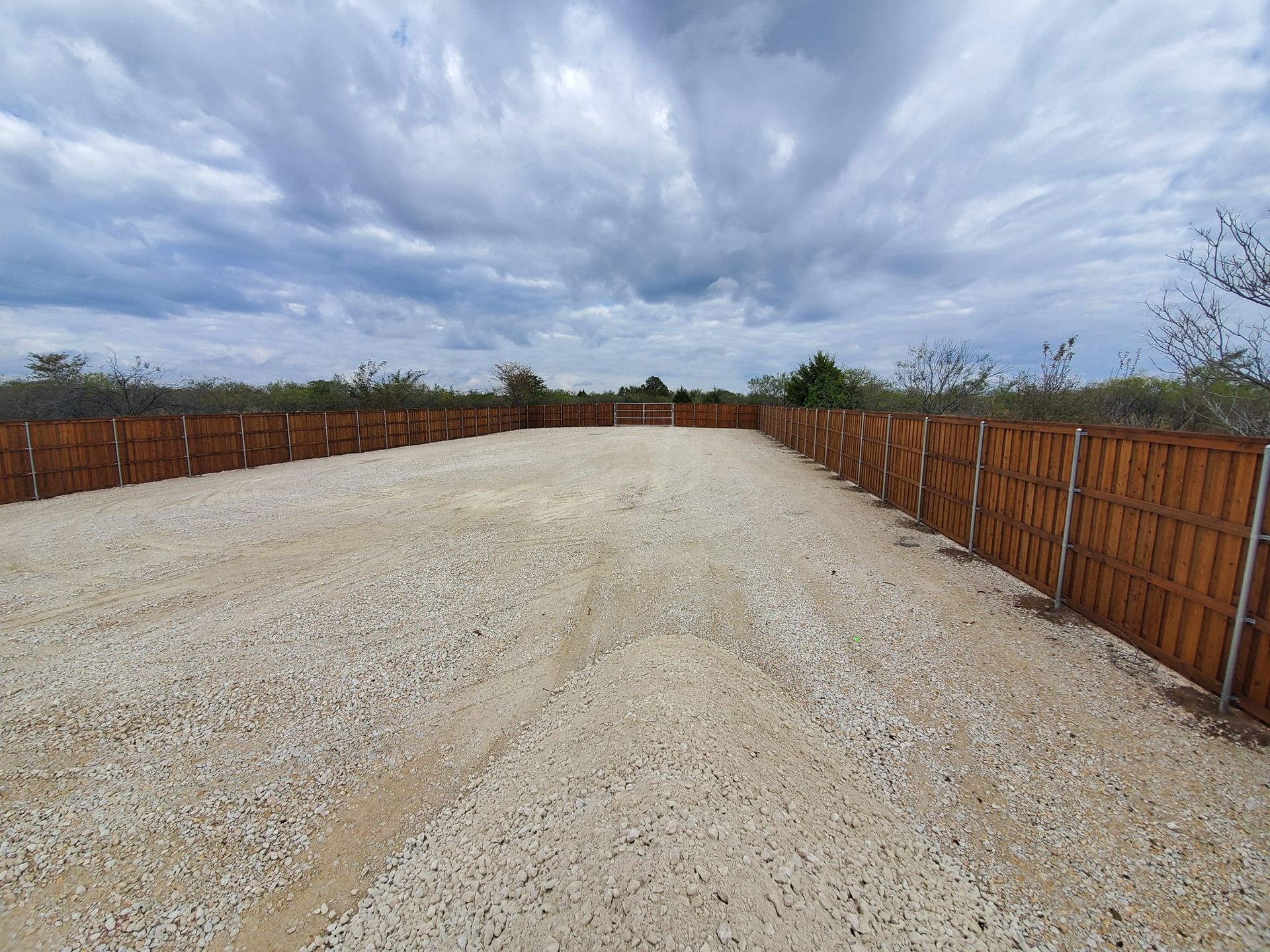 A gravel road with a wooden fence in the background