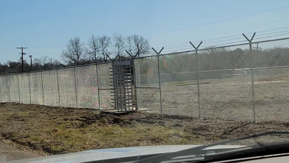 A fence with barbed wire is surrounding a field.