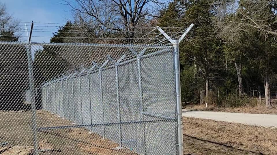 A chain link fence with barbed wire on top of it.