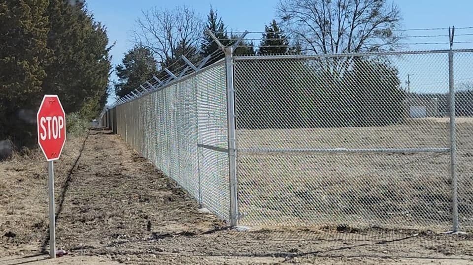 A stop sign is next to a chain link fence