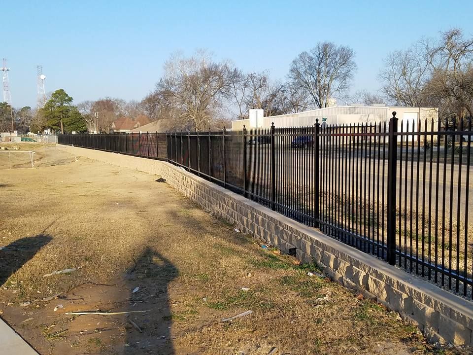 A shadow of a person is cast on the ground next to a fence
