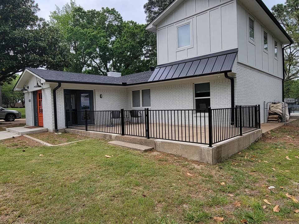 A white house with a black fence and a black roof.