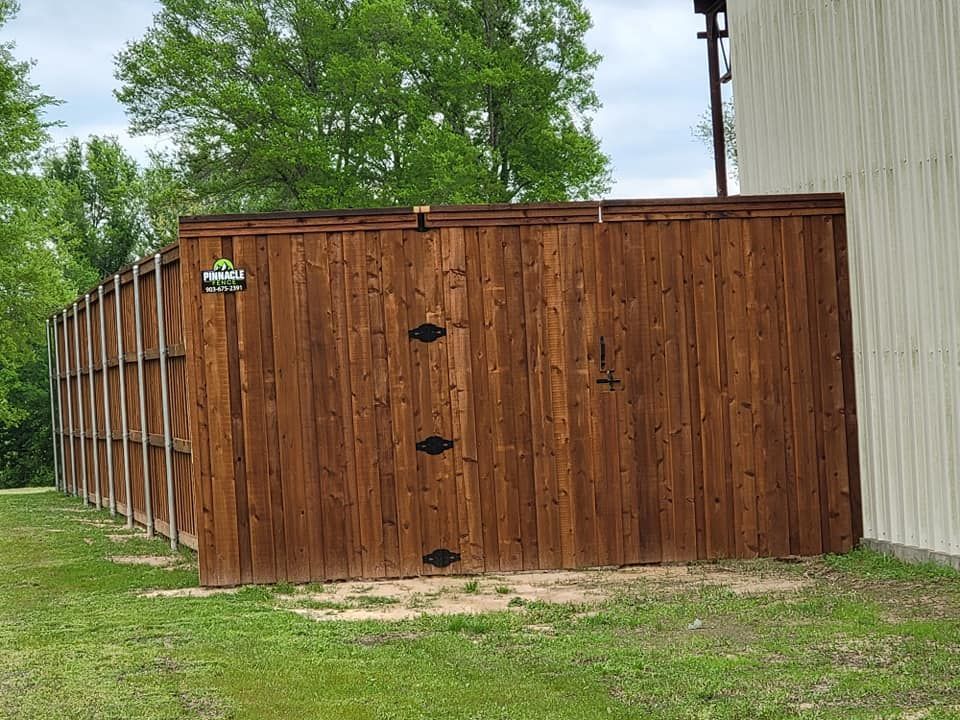 A wooden fence is sitting in the grass next to a building.