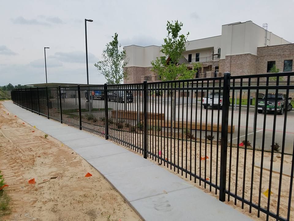 A black metal fence along a sidewalk in front of a building.