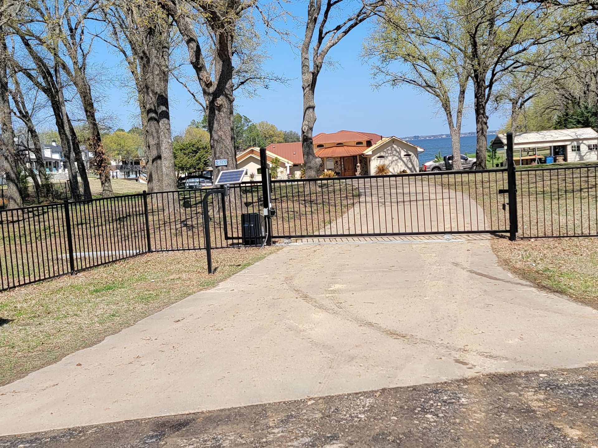 A driveway with a metal gate leading to a house.