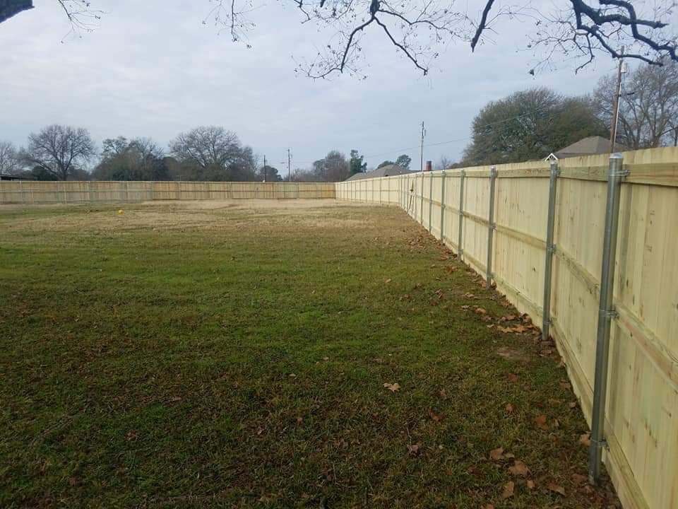 A wooden fence surrounds a large grassy field.