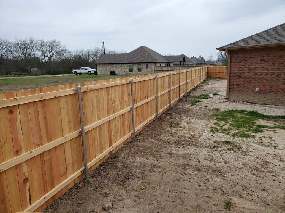 A wooden fence is in the backyard of a house.