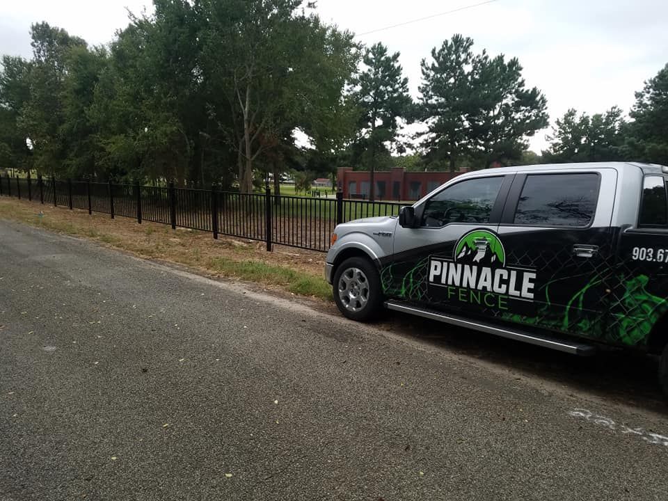 A pinnacle fence truck is parked on the side of the road.