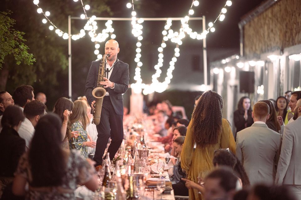 A saxophone player walks on the tables during a luxury wedding in Provence, South of France.